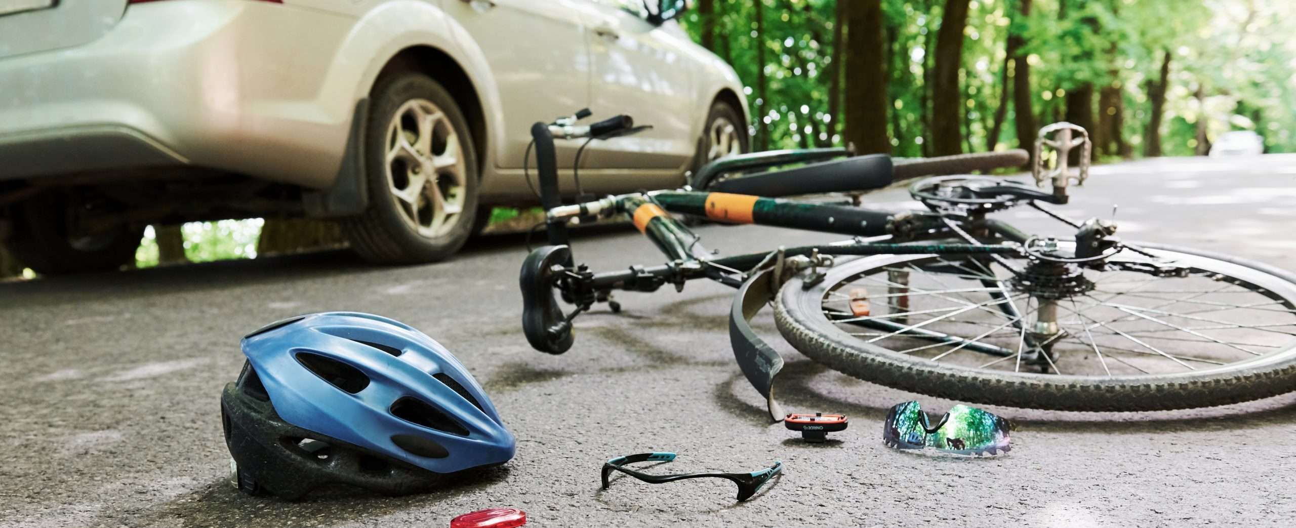 Danger place. Bicycle and silver colored car bicycle accident lawyer on the road at forest at daytime.