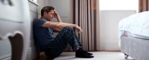 depressed man wearing-pajamas sitting on floor- emotional distress after an accident