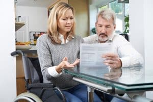 Middle age couple-wheelchair looking over injury settlement document and discussing subrogation