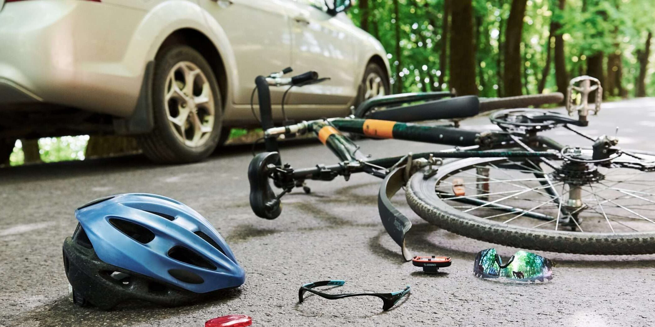 Danger place. Bicycle and silver colored car bicycle accident lawyer on the road at forest at daytime.