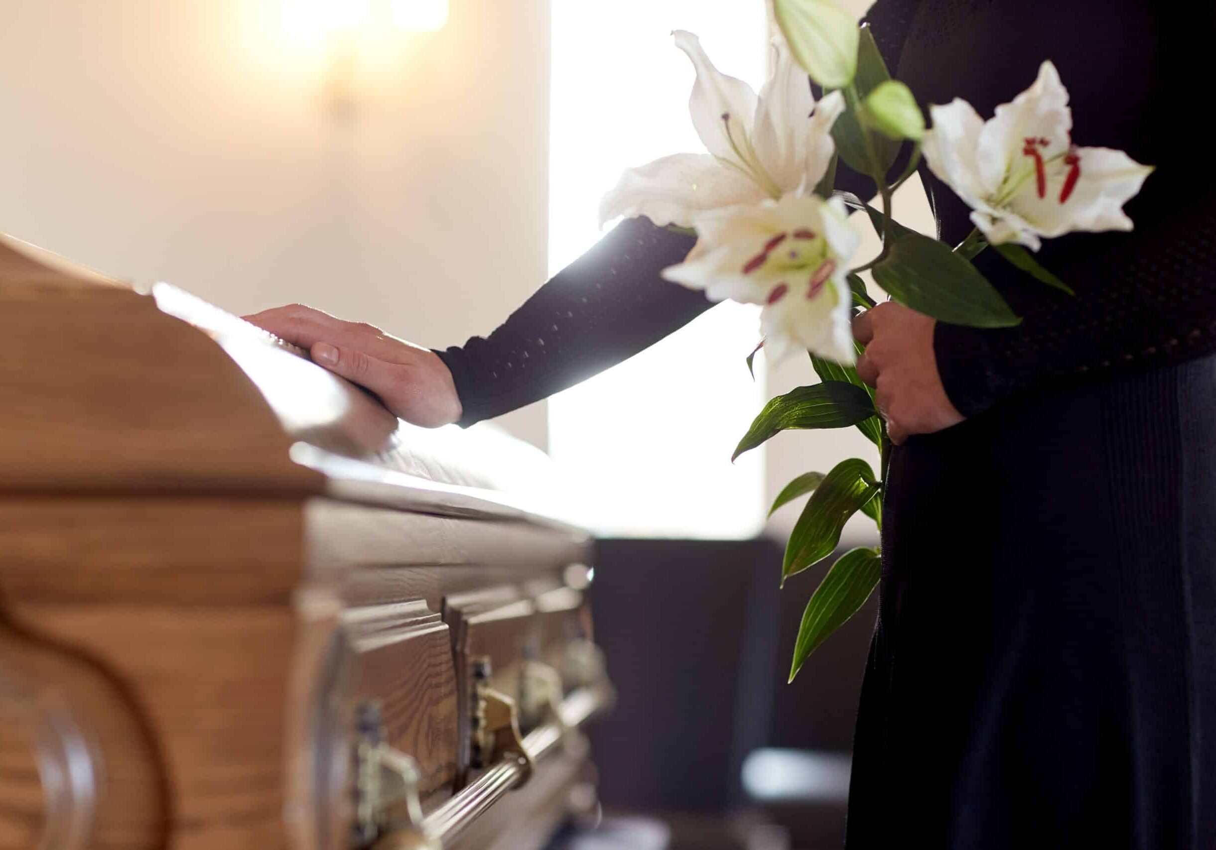 Woman with lily flowers and coffin at funeral after a wrongful death case